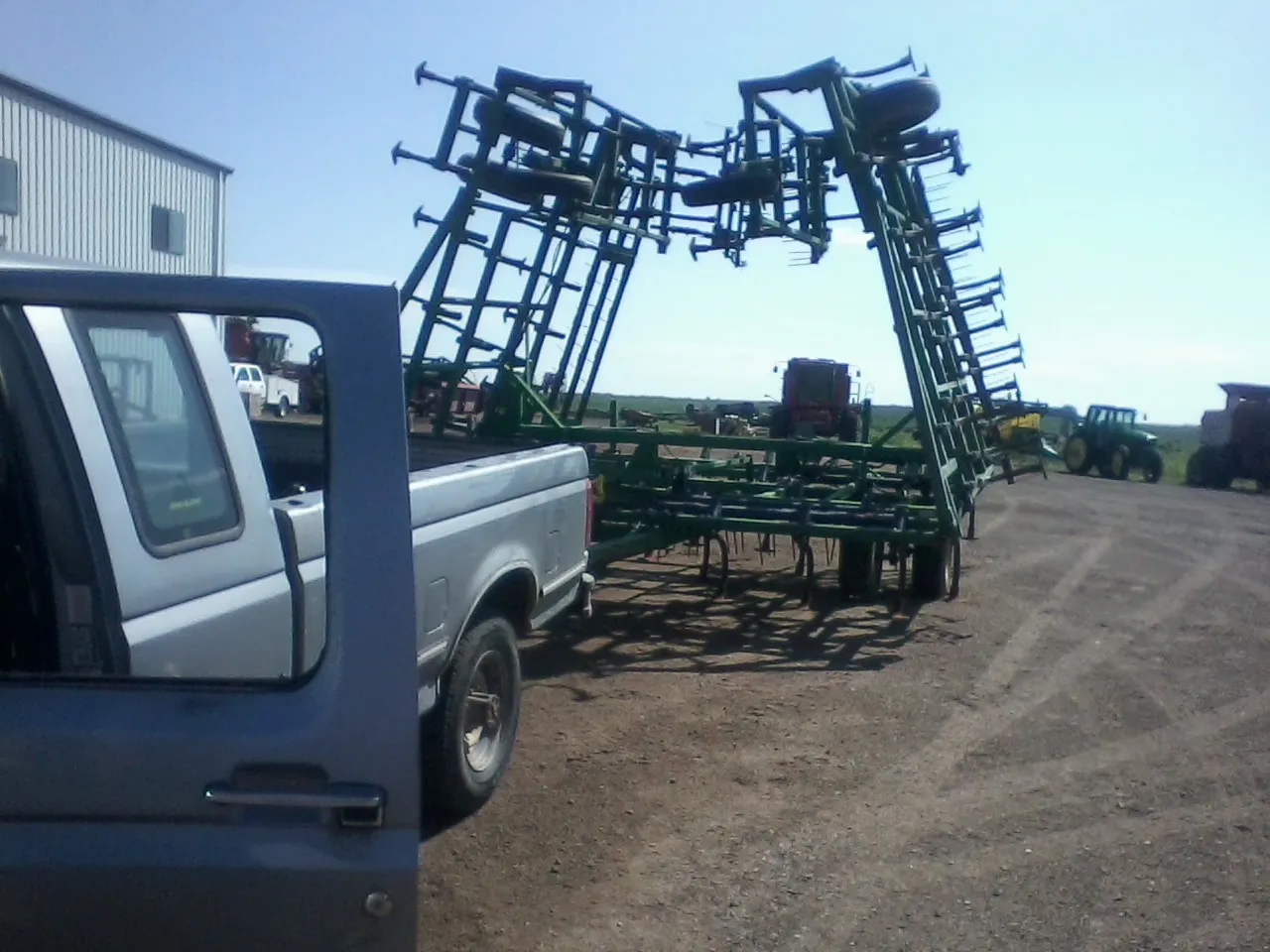 Cultivator with its frame folded up behind a pickup truck in a yard