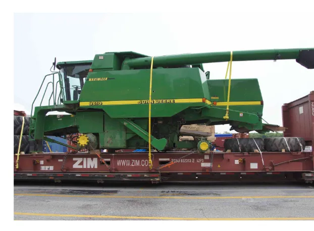 John Deere 9610 combine strapped onto a flat rack, with large tires placed beside it