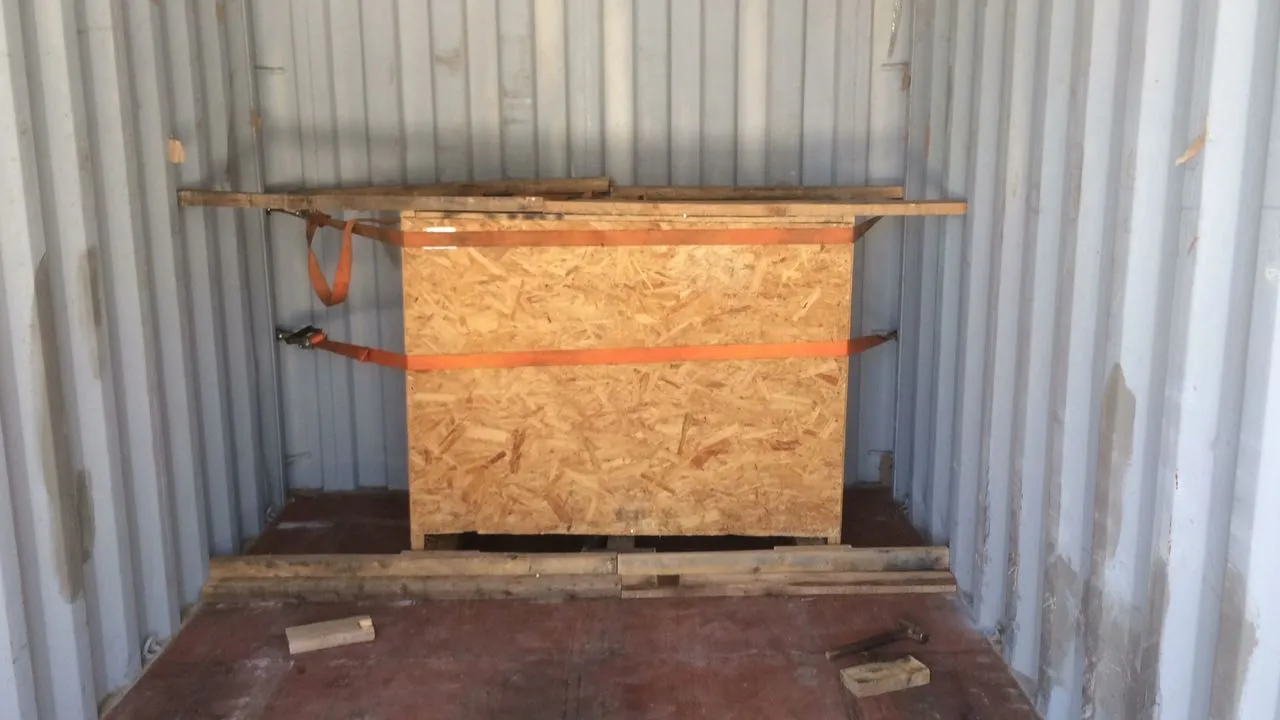 A wooden crate strapped down inside an empty container