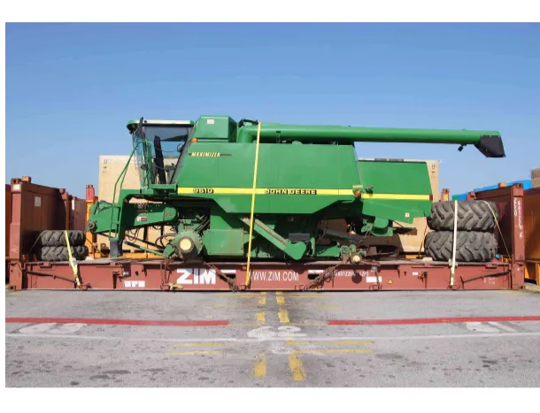 Комбайн John Deere на платформе flat rack в контейнерной зоне, рядом стопка шин