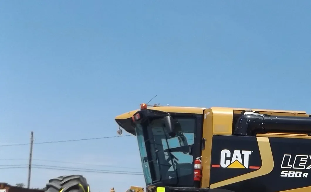 Front of a combine cab with a fire extinguisher beside the door under a clear sky