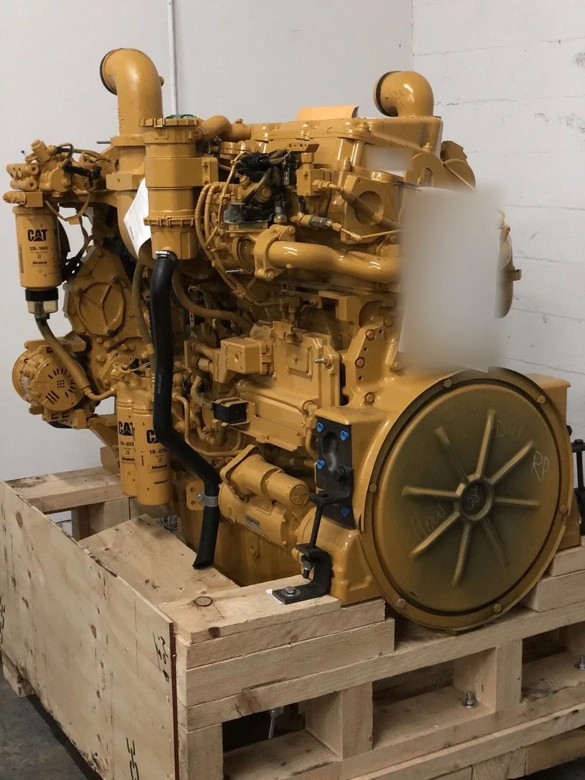 A CAT engine on a wooden shipping cradle in front of a white wall