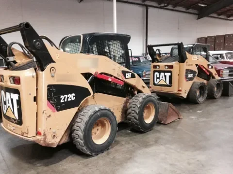 Two Caterpillar loaders parked side by side on a warehouse floor
