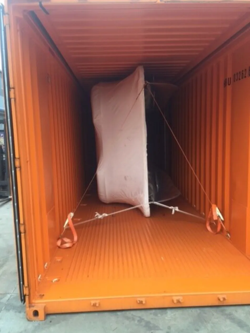 A boat in pink protective film held by straps inside an orange container