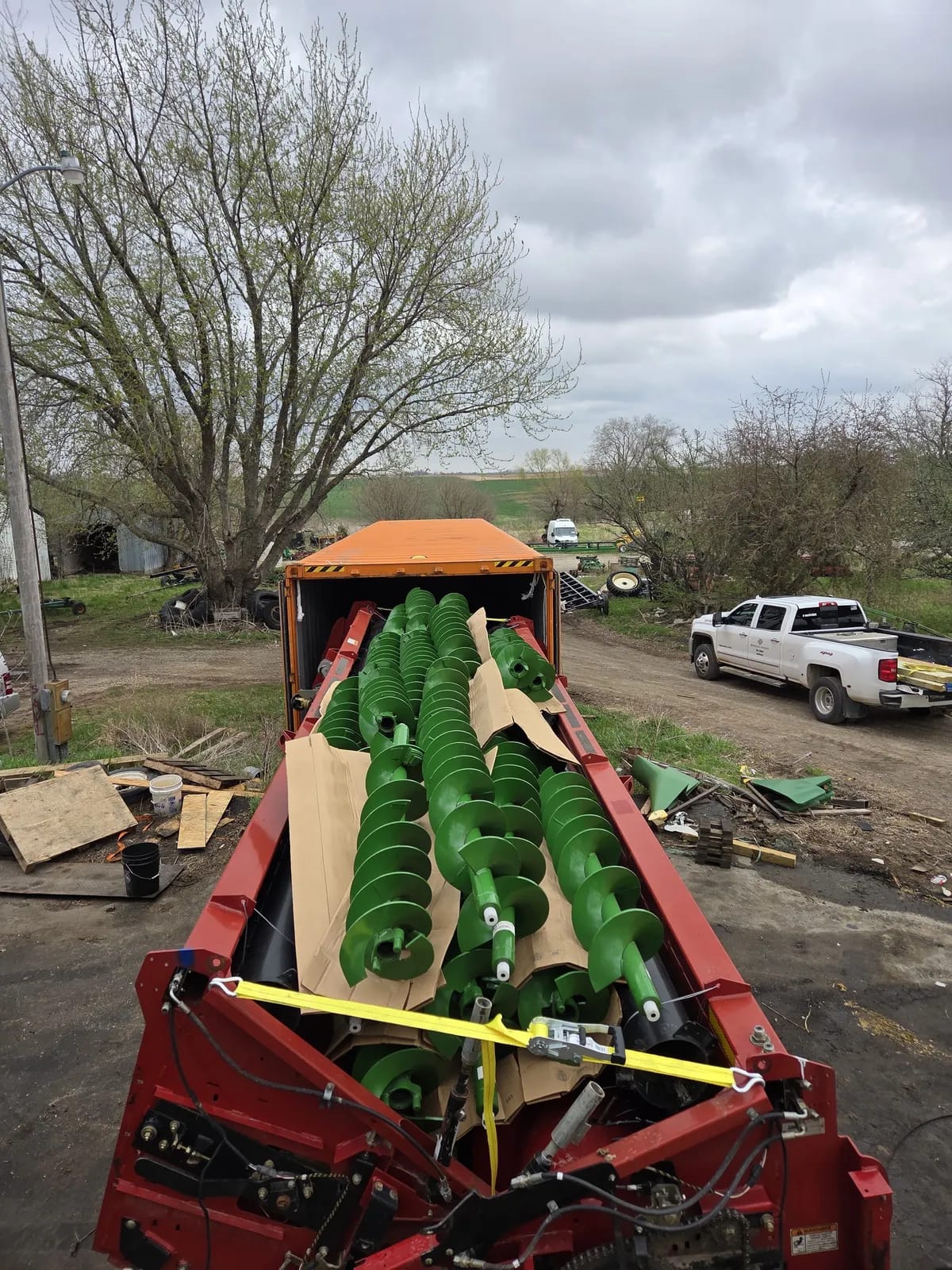 Auger screws packed in cardboard on a red loading frame with a yellow strap across them