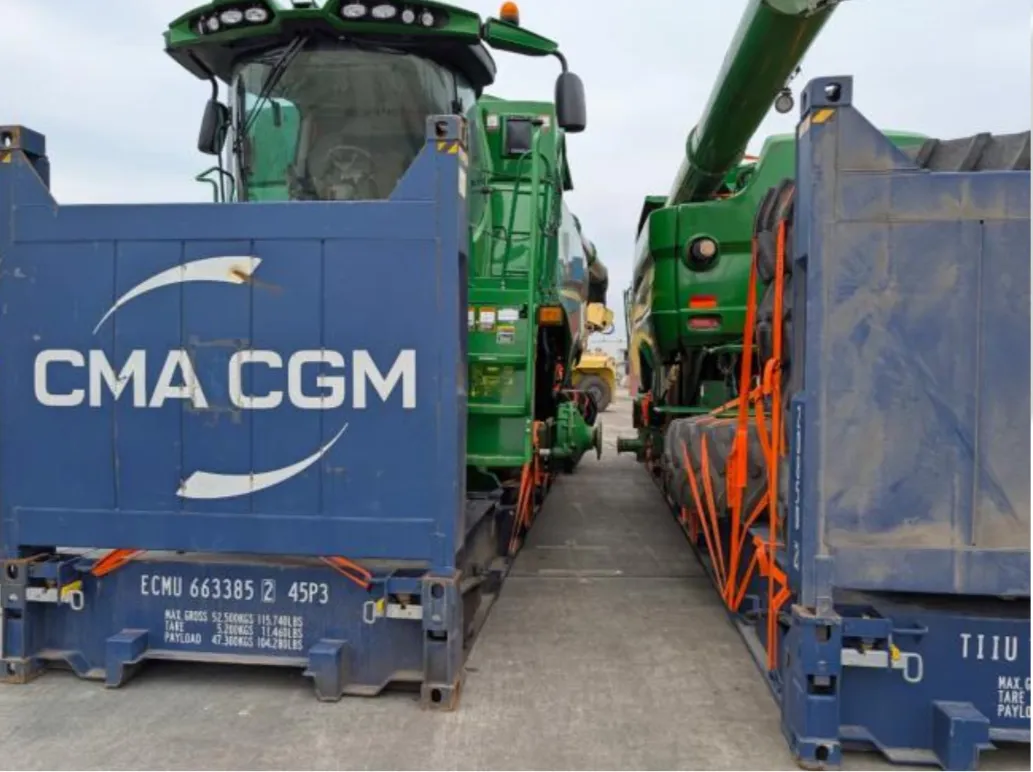 Два комбайна John Deere на платформах flat rack рядом друг с другом на портовой площадке