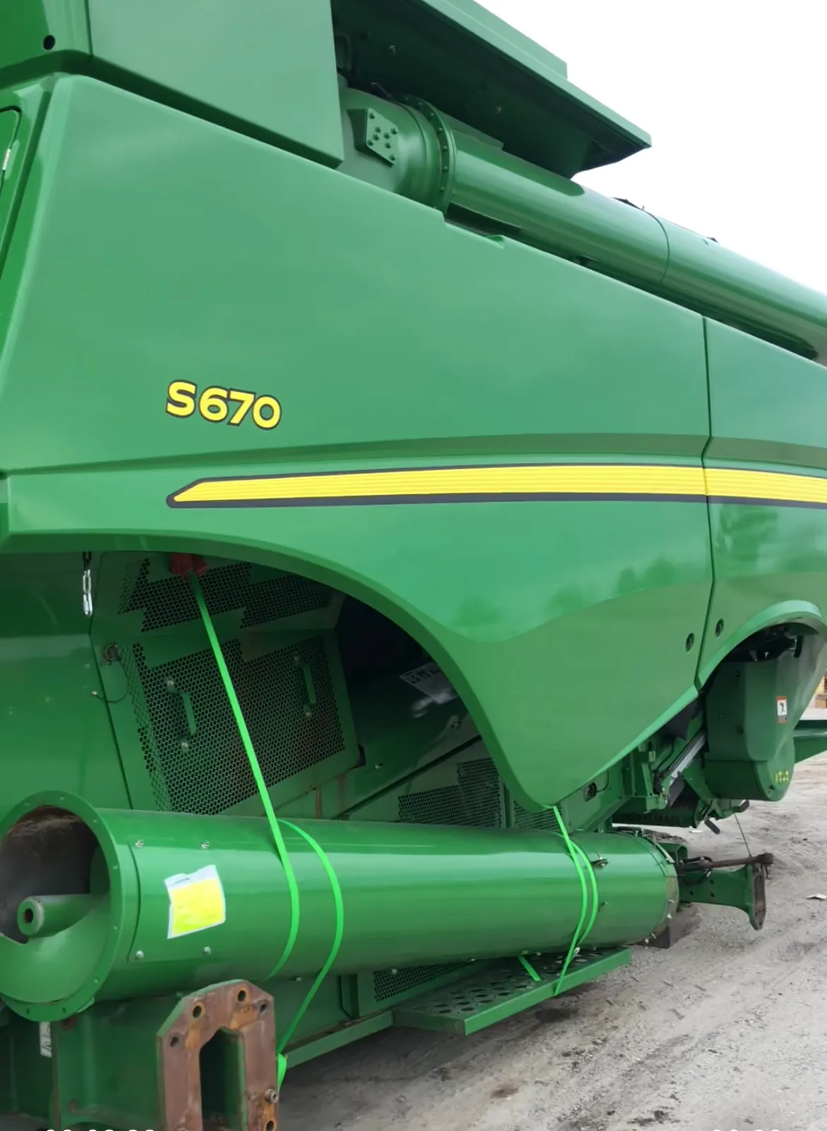 Комбайн John Deere S670 сбоку: зелёный ремень поперёк решётки моторного отсека и крупная зелёная труба внизу