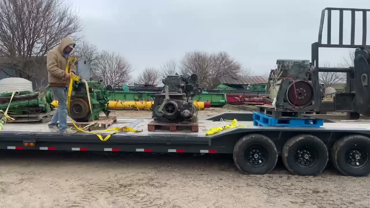 Used engines on pallets strapped to a flatbed trailer in a yard