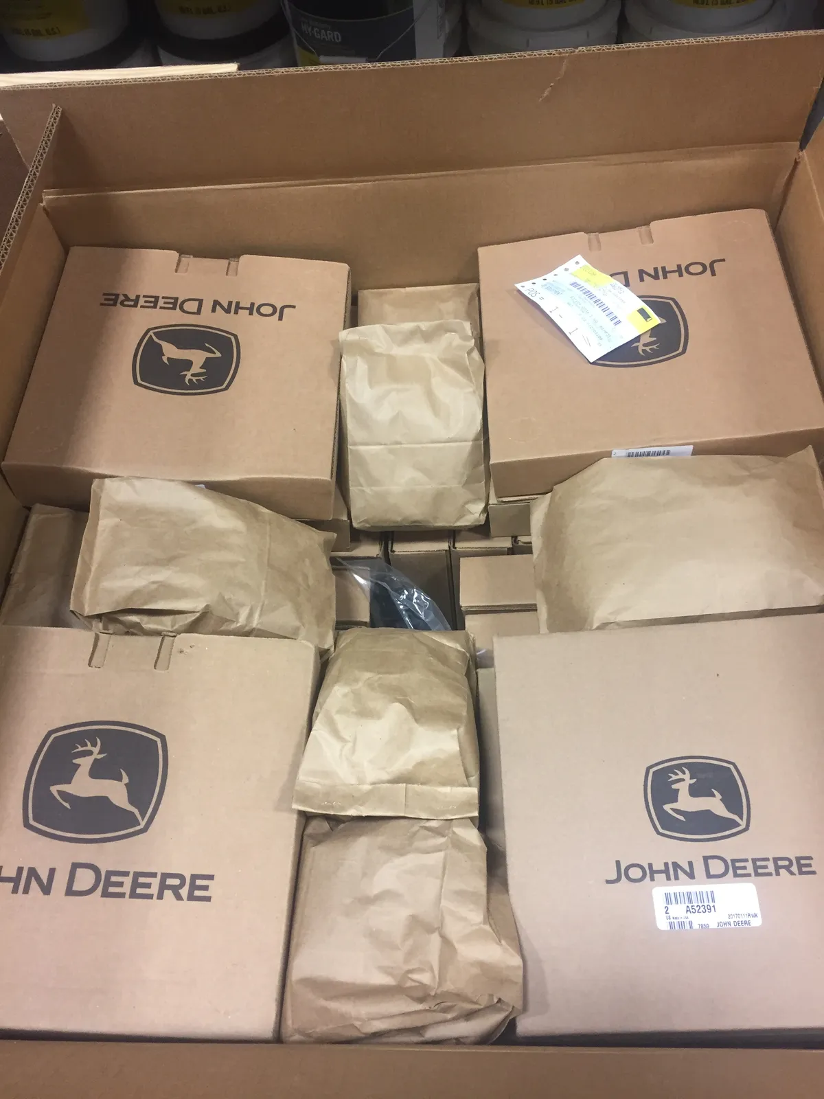 Ящик, заполненный коробками с запчастями John Deere и свёртками в бумаге