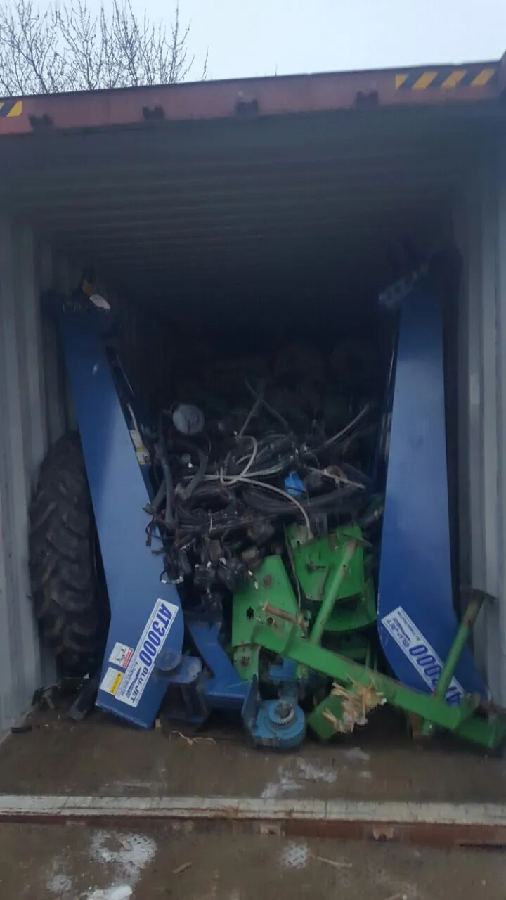 Rear of a container packed with frames marked AT3000, hoses and a wheel