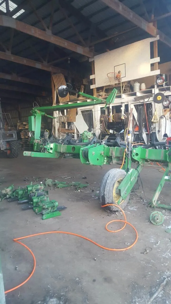 Implement frame in green raised inside a workshop, with components lying on the floor