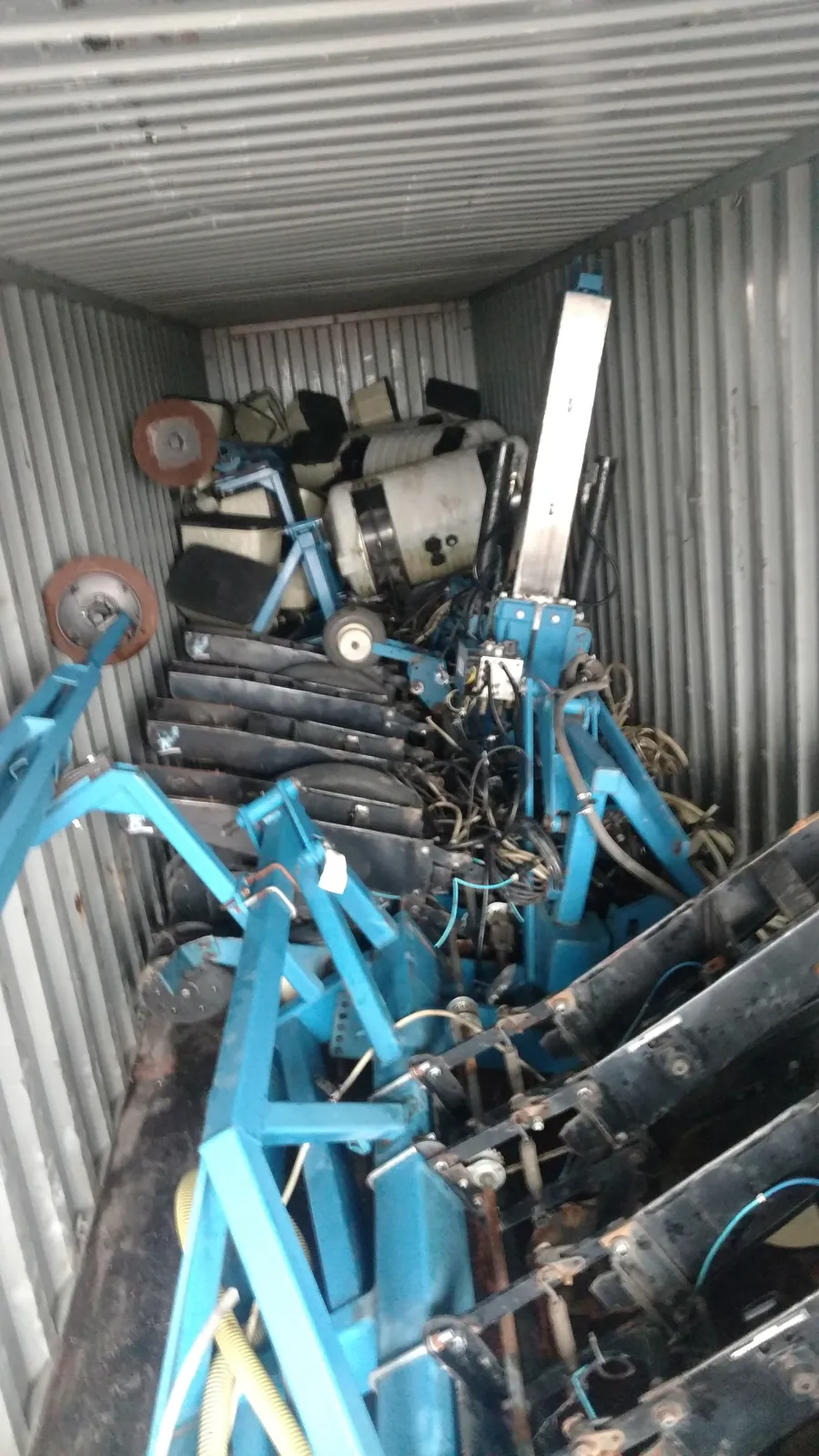 Dismantled planter frame sections and white tanks packed inside a container