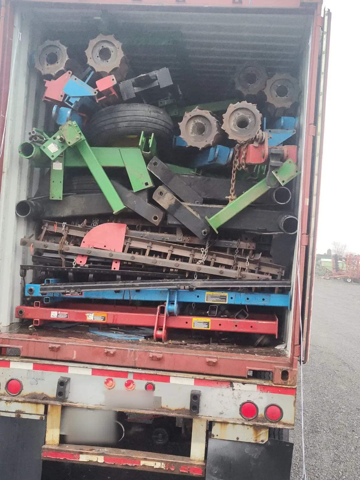 Container opened at the back, packed tightly with disassembled cultivator frames, wheels and sprocket parts