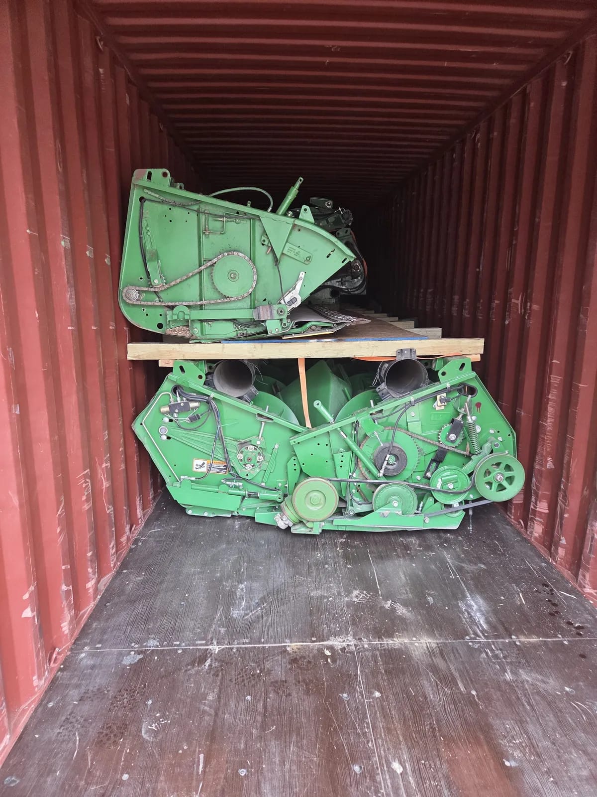 Flex headers stacked on a wooden platform inside a shipping container