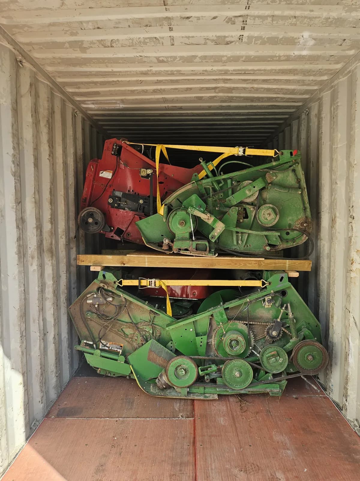 Inside a container: red and green headers on a wooden deck above a green header, held by yellow straps